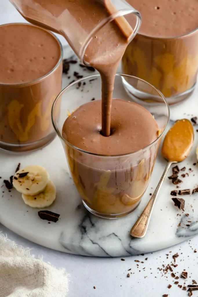 A rich chocolate peanut butter bulker smoothie in a tall glass, made with Muscle Milk Gainer, peanut butter, banana, oats, and whole milk, ready for mass gain.