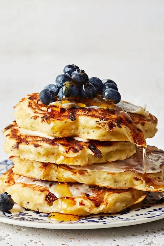 A stack of golden high-protein pancakes, made using Muscle Milk Mass Gainer, eggs, and milk, with a light drizzle of syrup, for a muscle-building breakfast.